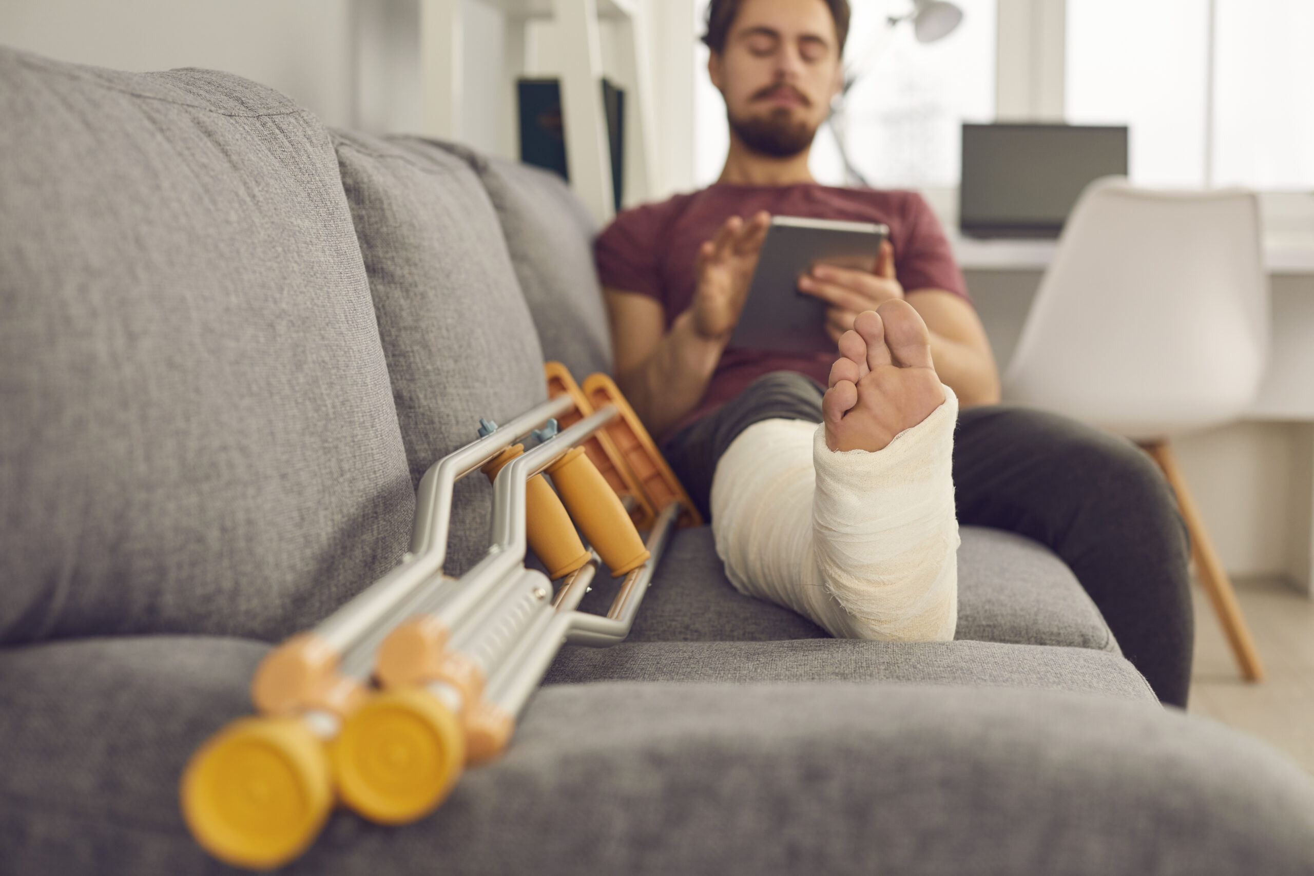 Injured man on sofa with crutches. 