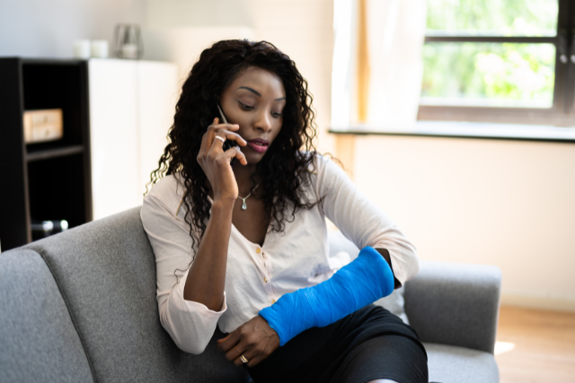 Woman in a arm cast on the phone calling a personal injury lawyer.