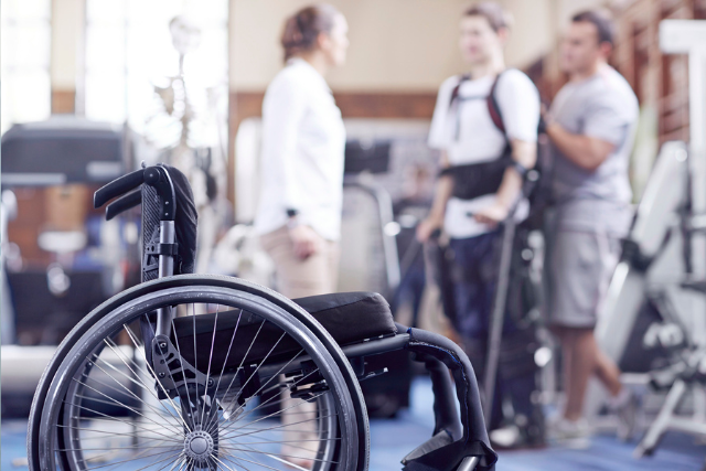 Man receiving physical therapy with wheelchair in foreground.