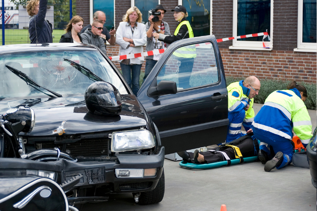 Bystanders watching as emergency team assist an injured person in an accident. 