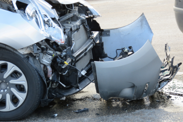 Image of a car with its bumper knocked off on the road.